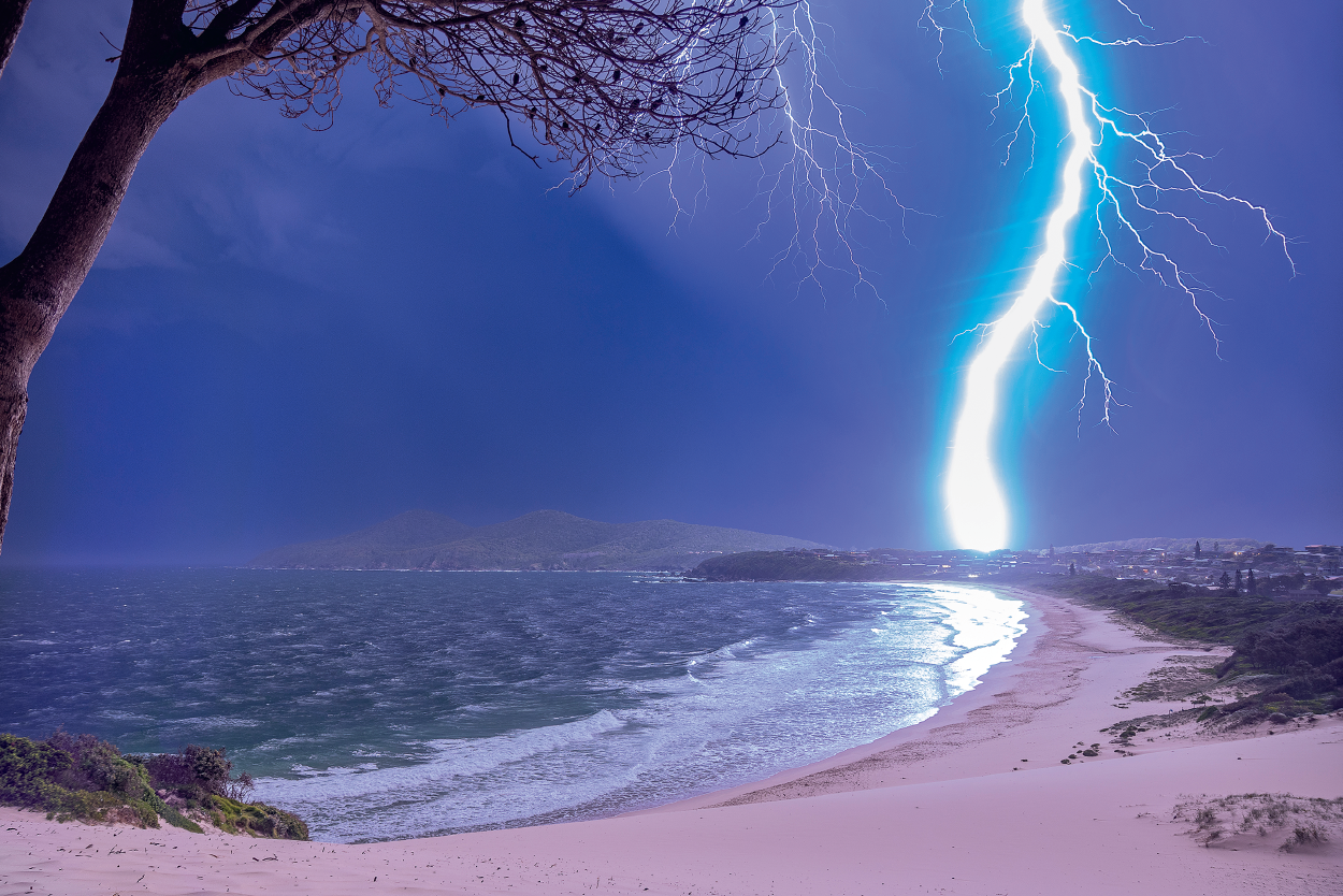 Very bright lightning strikes an empty beach.