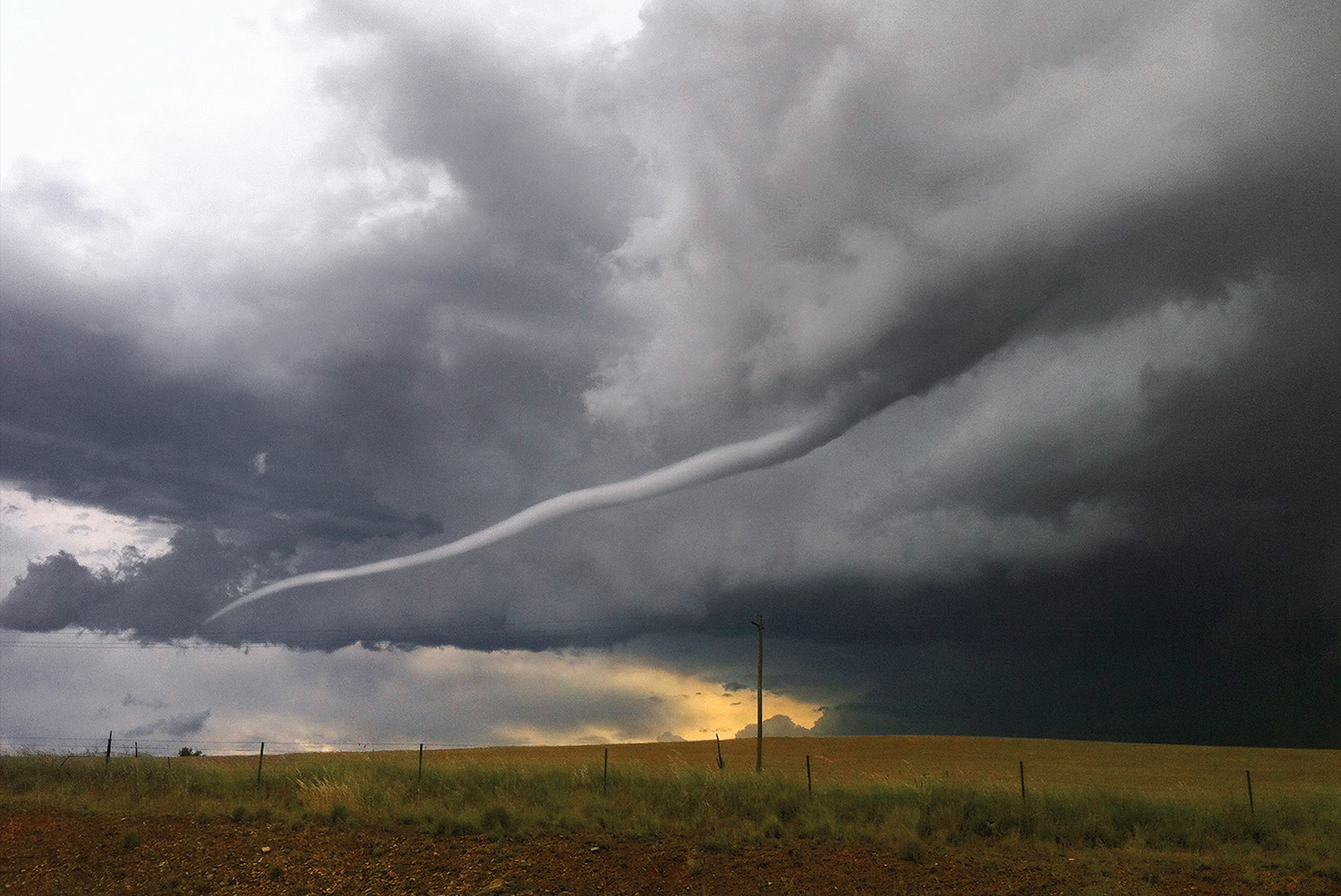 Funnel cloud reaching down from dark, clouded sky