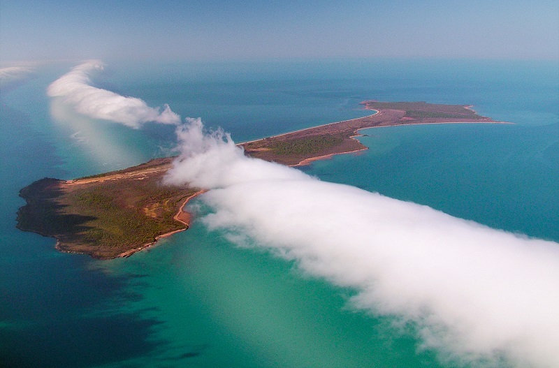Taken from the air, this image looks down on a long white cloud above Sweers Island, surrounded by turquoise seas.