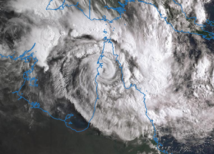 Satellite image with Australia's edge visible as a blue line over the clouds, which display the classic cyclone spiral band patter.